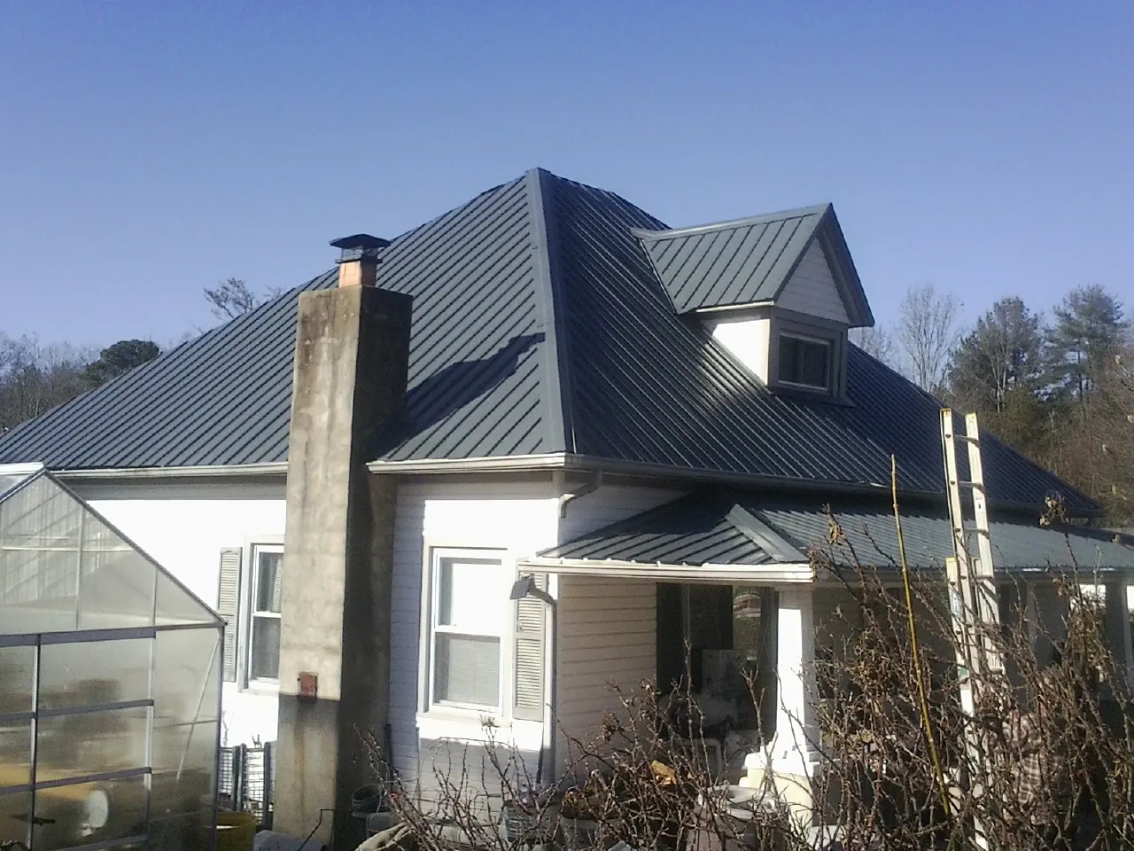 Dark blue standing seam metal roof on a white farmhouse with dormer — Slate & Tile Roof Repair by Roofing Brothers in Healdsburg
